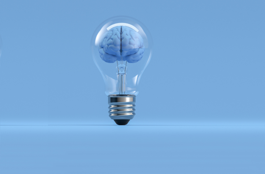 Clear light bulb with brain inside against blue background.