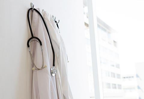 Doctor's coat and stethoscope hanging on the back of a door