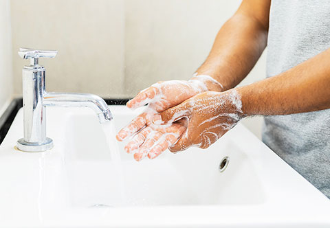 Person lathering their hands with soap at a sink